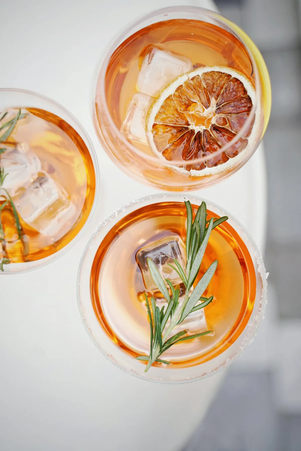 Trije oranžni spritz koktajli z ledom in rožmarinom, pogled od zgoraj