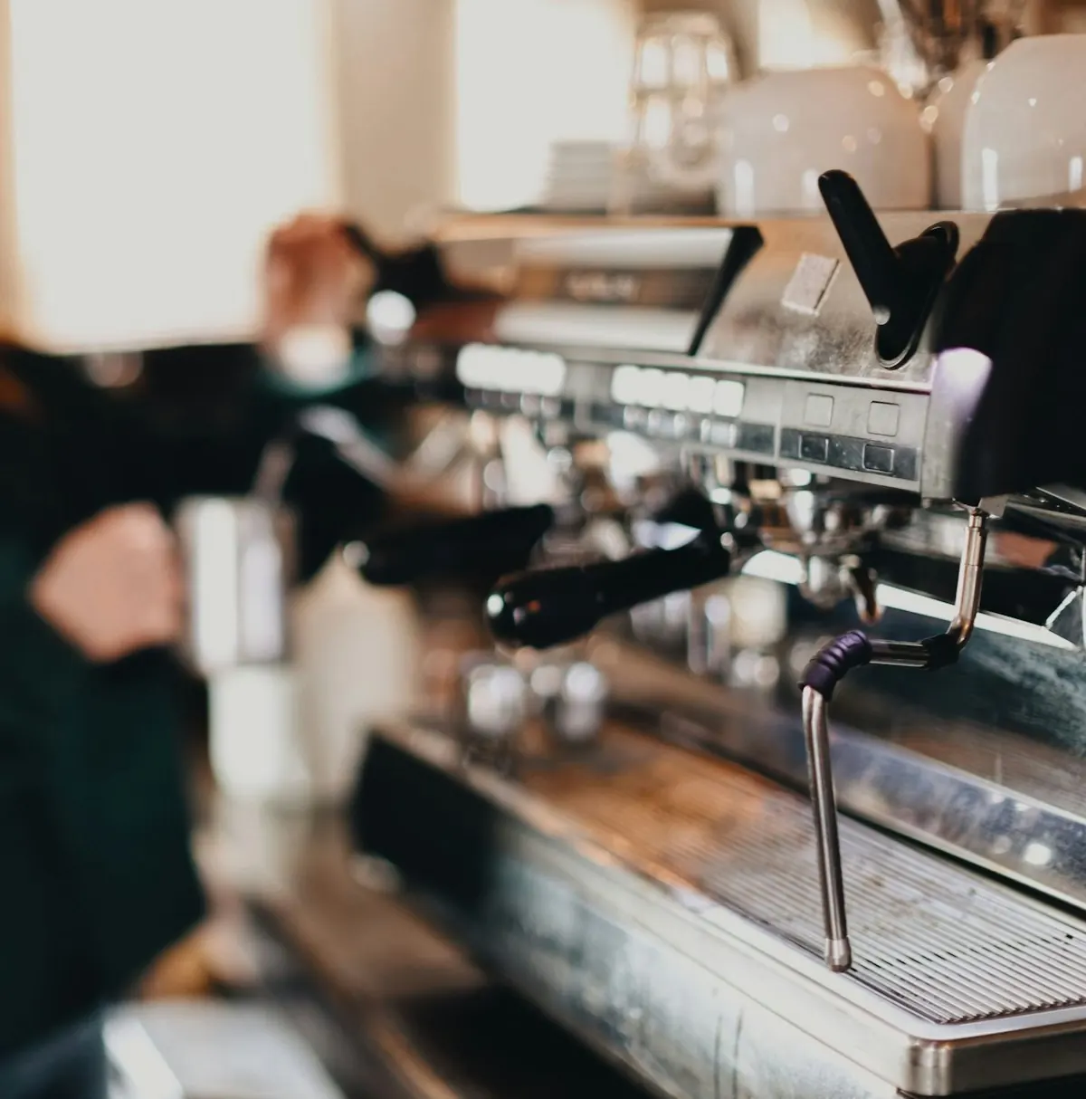 Barista za nerjavečim espresso aparatom